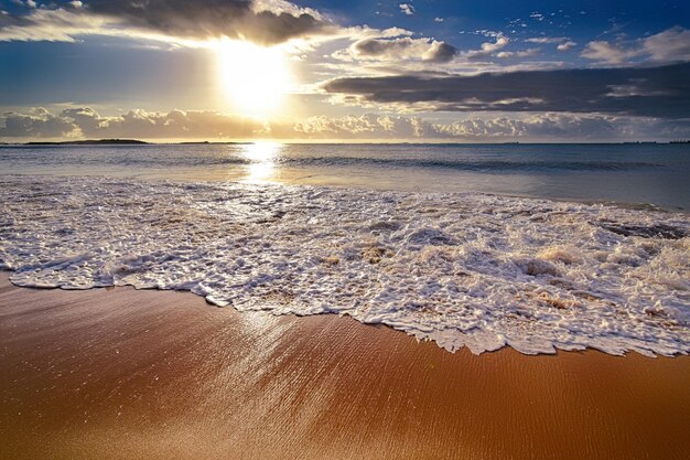 As ondas do oceano rolando sobre a praia durante o nascer do sol