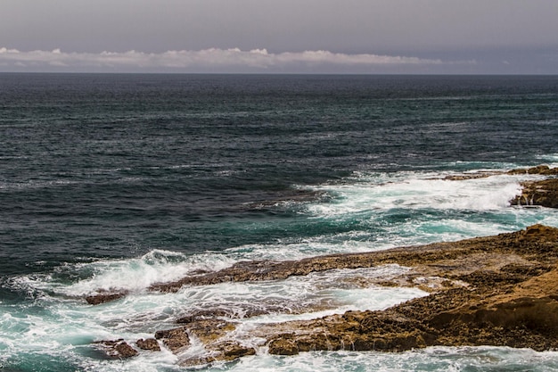 As ondas lutando sobre a costa rochosa deserta do Oceano Atlântico Portugal