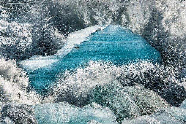 As ondas quebram e criam feixes de espuma nos blocos de gelo rejeitados na praia de Jokulsarlon