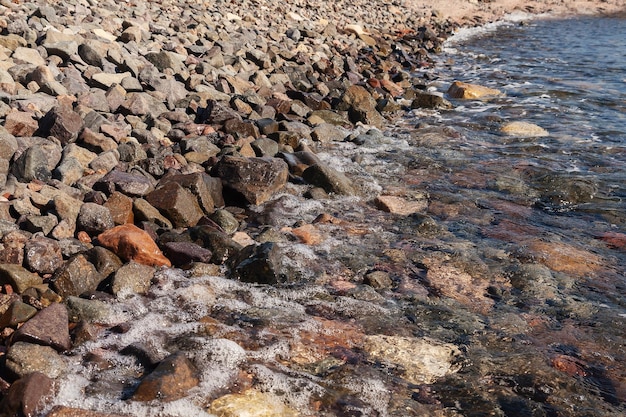 As ondas rolaram na praia com seixos