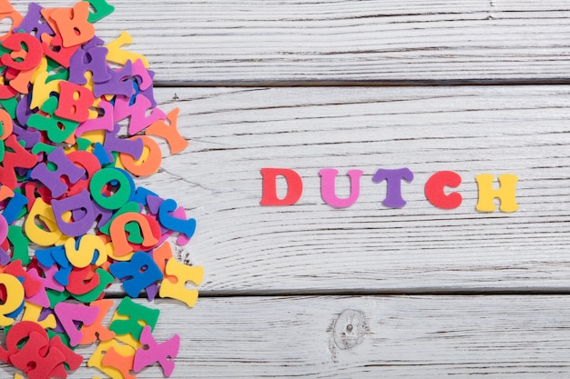 As palavras coloridas holandês feitas com letras coloridas sobre uma placa de madeira branca
