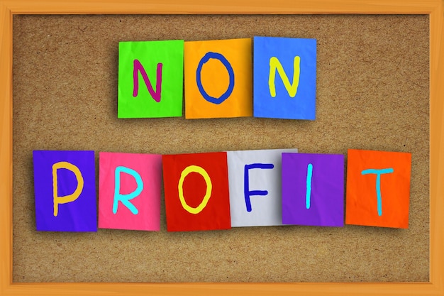 As palavras "Non Profit" escritas em papel colorido pegajoso sobre uma placa de cortiça.