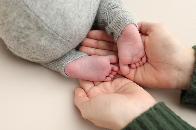 Foto as palmas das mãos do pai, a mãe segurando o pé do bebê recém-nascido, os pés do recém-natado nas palmas dos pais, foto macro de estúdio dos dedos das mãos, dos calcanhares e dos pés das crianças em um fundo branco.