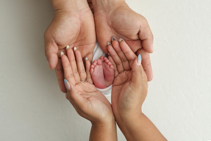 Foto as palmas das mãos dos pais um pai e uma mãe seguram os pés de uma criança recém-nascida em um cobertor branco em um fundo branco os pés de um recén-nascido nas mãos dos pais foto de calcanhar e dedos dos pés