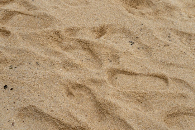 As pegadas de textura na areia da praia fecham