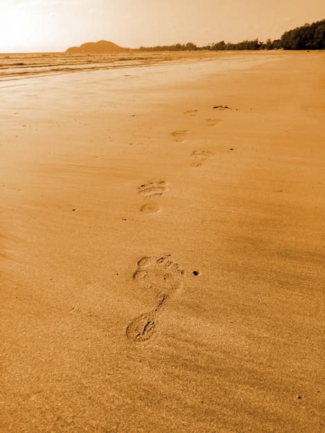 Foto as pegadas do homem na praia de areia em férias de férias relaxante tempo