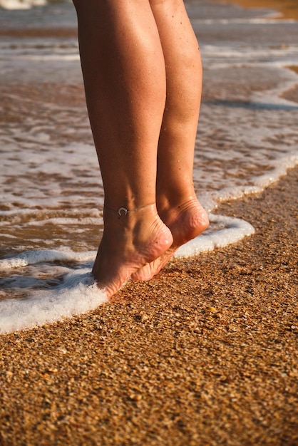 As pernas da mulher fecham-se na areia e na beira-mar