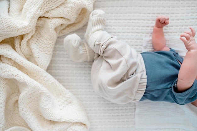 As pernas de um bebê recém-nascido em um cobertor branco