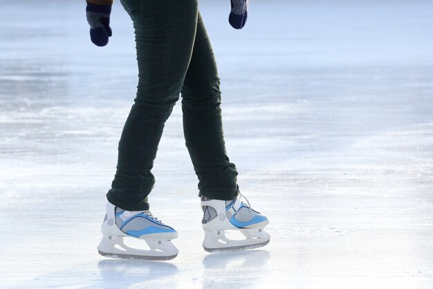 As pernas de um homem patinando na pista de gelo