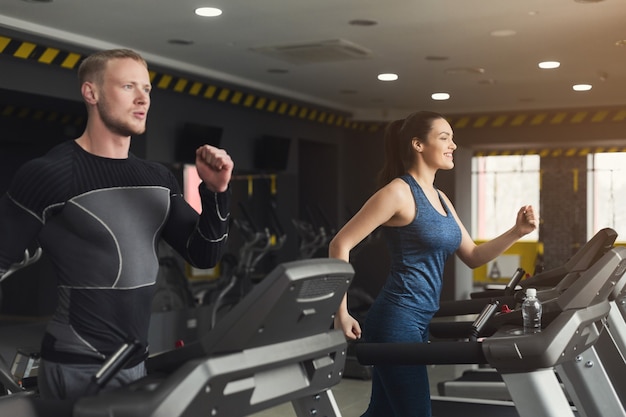 As pessoas correm em esteiras. Homens e mulheres treino cardiovascular no clube de fitness. Estilo de vida saudável, treinamento na academia, espaço de cópia