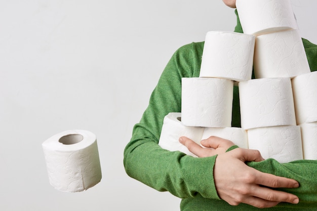 As pessoas estão estocando papel higiênico para casa. Mulher com muitos rolos de papel higiênico. Espaço para texto.