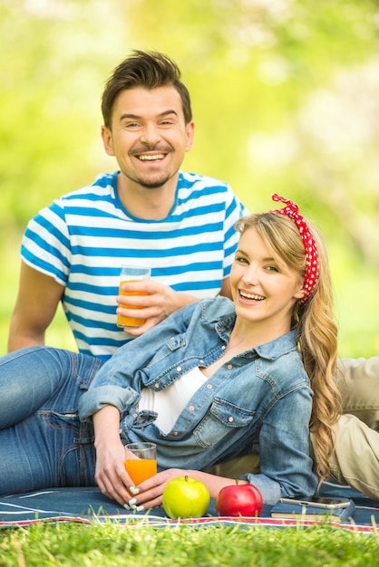 As pessoas estão fazendo piquenique no parque e bebendo suco.