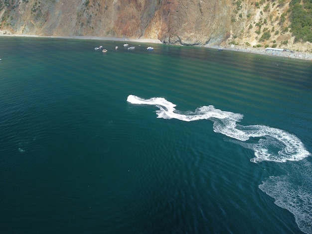 As pessoas estão jogando jet ski no mar, deixando pegadas brancas abstratas no topo da água