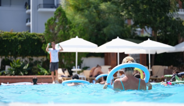 As pessoas fazem aeróbica aquática na piscina de macarrão.