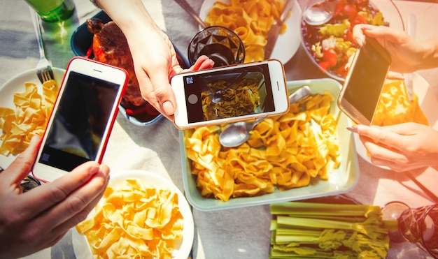 As pessoas fazem uma imagem de comida para rede social antes de estarem comendo frango e espaguete. Acima vista