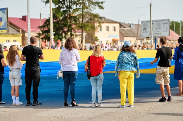 Foto as pessoas seguram a bandeira ucraniana com as mãos eles olham para frente dia da bandeira da ucrânia