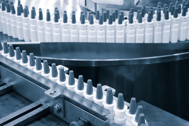 As pílulas de remédios da indústria farmacêutica estão enchendo a garrafa no transportador da máquina da linha de produção no foco seletivo da fábrica médica