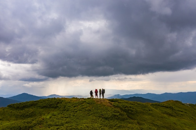 As quatro pessoas ativas em uma montanha contra a pitoresca vista da nuvem