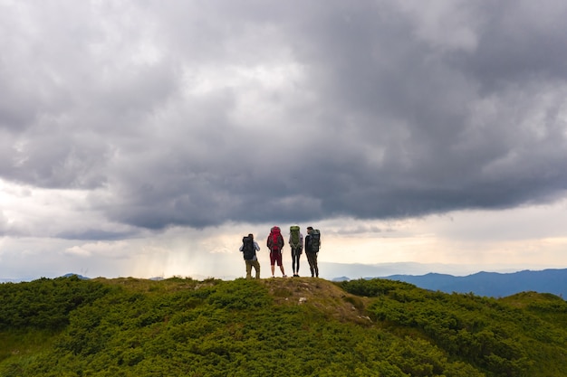 As quatro pessoas ativas em uma montanha contra a pitoresca vista da nuvem