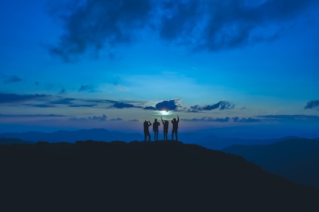 As quatro pessoas em pé na bela montanha ao fundo da lua