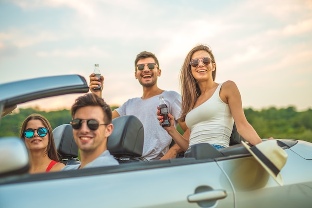 As quatro pessoas felizes sentam em um cabrio