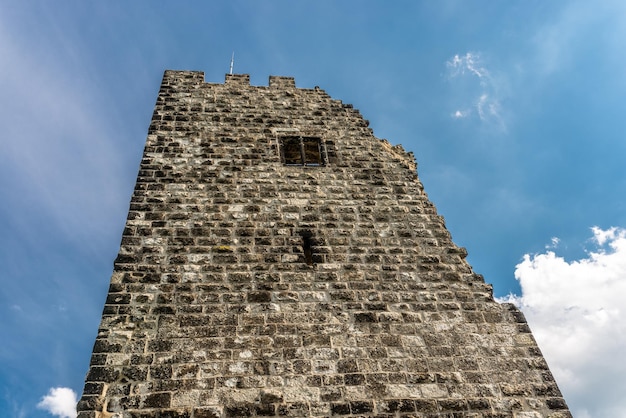 As ruínas de uma torre histórica contra um céu azul com nuvens brancas