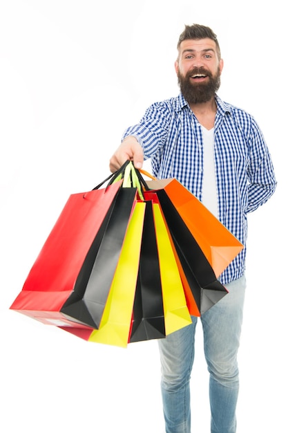 Foto as sacolas estão cheias feliz comprador hipster segurando sacolas de compras isoladas em branco homem barbudo sorrindo com sacolas de papel após a venda sazonal carregando compras de férias em sacolas coloridas