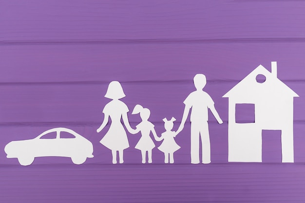 As silhuetas recortadas em papel de homem e mulher com duas meninas, casa e carro perto