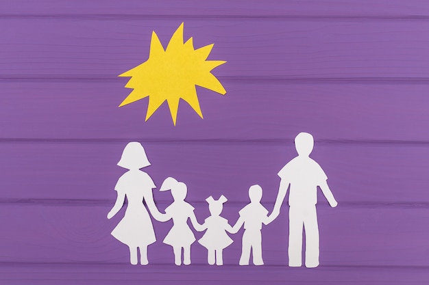 As silhuetas recortadas em papel de homem e mulher com duas meninas e menino sob o sol
