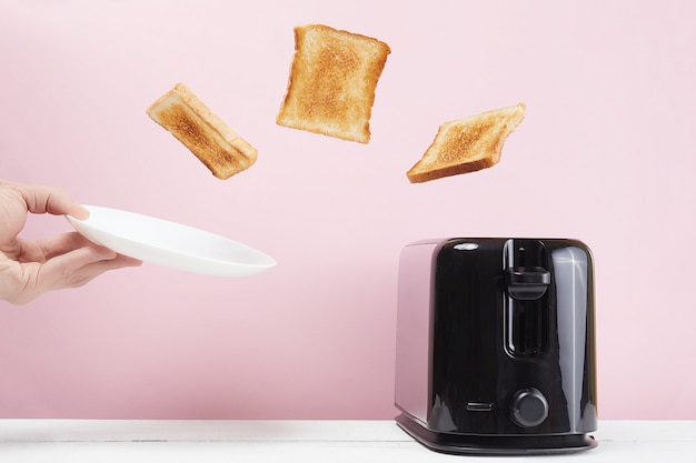 As torradas saíram da torradeira moderna. Perto de copo de leite. Comida e prato de levitação. Conceito de café da manhã delicioso