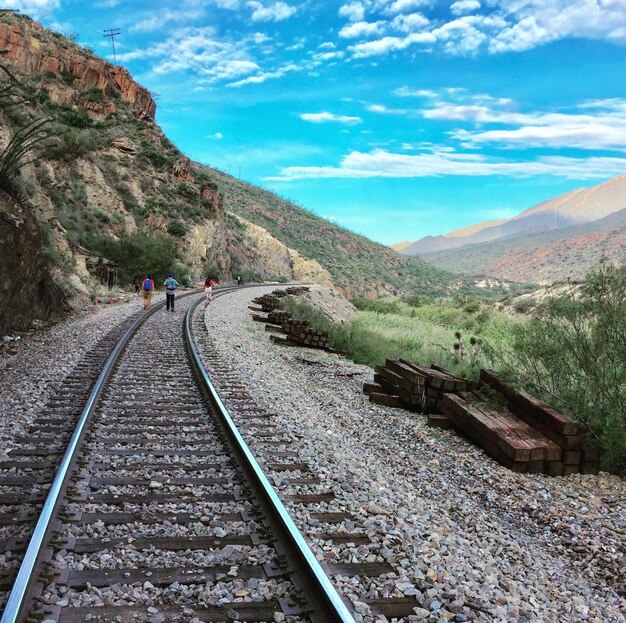 Foto as trilhas da ferrovia em meio às montanhas contra o céu