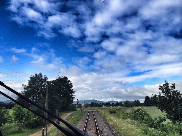 Foto as trilhas da ferrovia no campo contra o céu nublado