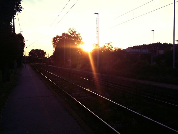 Foto as trilhas do caminho-de-ferro contra o céu durante o pôr-do-sol