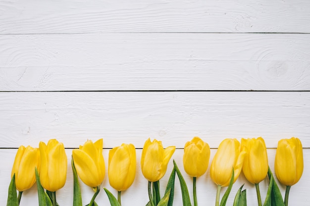 As tulipas amarelas ajuntam-se no backgropund rural da tabela do celeiro rústico de madeira das pranchas. Espaço vazio para letras, texto, cartas, inscrição. Modelo horizontal bonito cartão postal leigos.