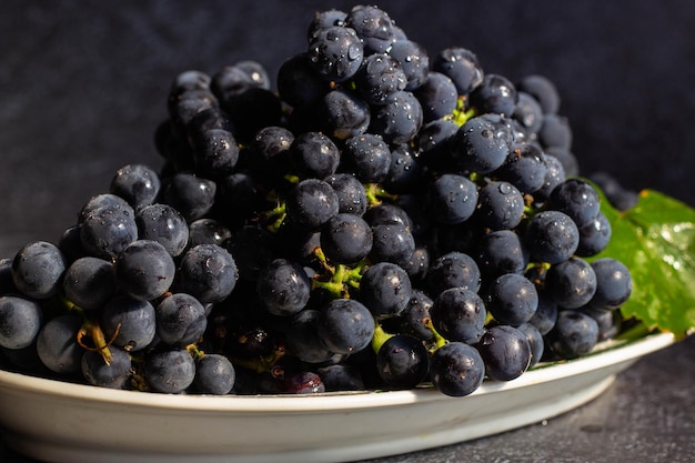 As uvas pretas estão em um prato branco com uma faixa verde oval