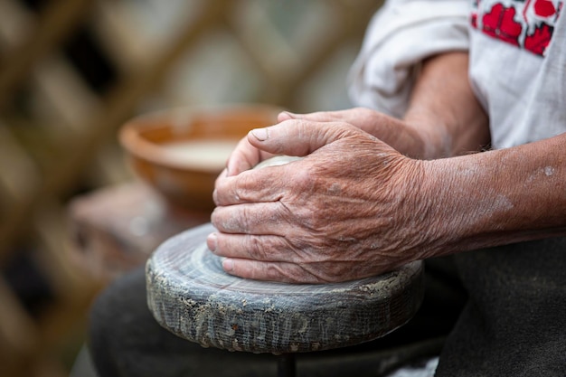 As velhas mãos do mestre fazem produtos de barro Trabalho na roda do oleiro