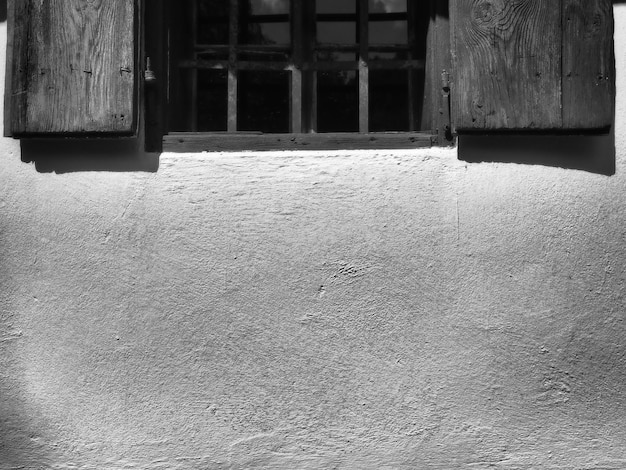 As velhas venezianas de madeira estão abertas As molduras das janelas e venezianas de madeira são pintadas de azul Espaço para texto Muro de concreto branco Arquitetura rústica tradicional