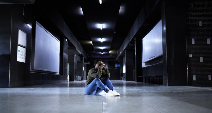Foto às vezes, tudo fica demais foto de corpo inteiro de uma jovem parecendo deprimida enquanto está sentada no chão de um terminal de estação de trem