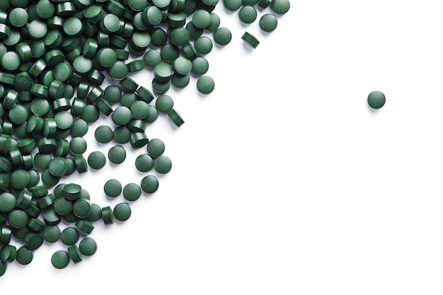 As vitaminas vegetarianas da Spirulina estão espalhadas em um fundo branco com espaço livre