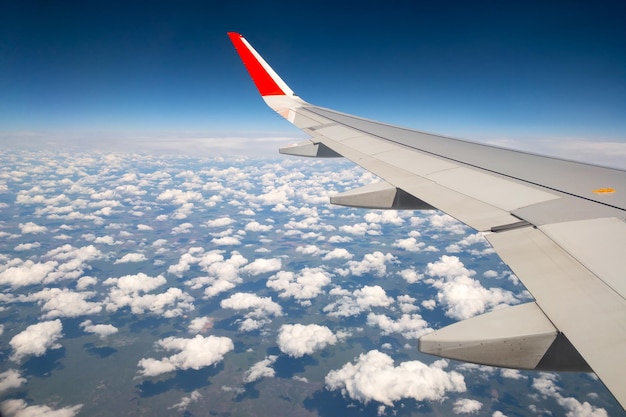 Asa de avião com céu azul claro e nuvens brancas sobre a viagem terrestre de verão ou o conceito de férias