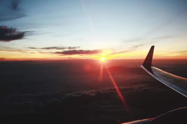 Foto asa de avião contra o céu durante o pôr do sol