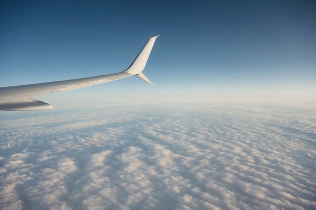 Asa de avião voando nublado no céu azul