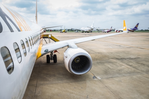 Asa do detalhe da turbina do avião no aeroporto no campo à espera ou espere o passageiro.