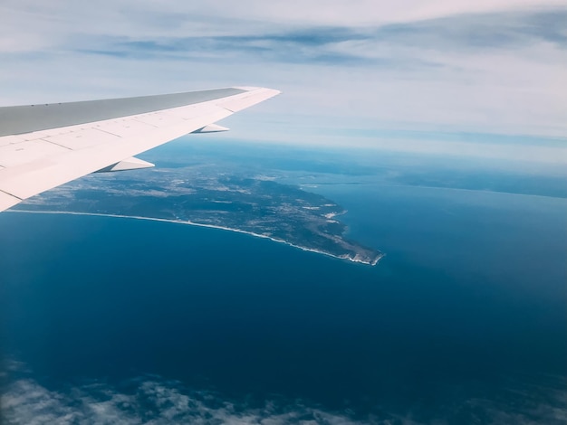 Asa pela janela do avião no céu incrível ao pôr do sol