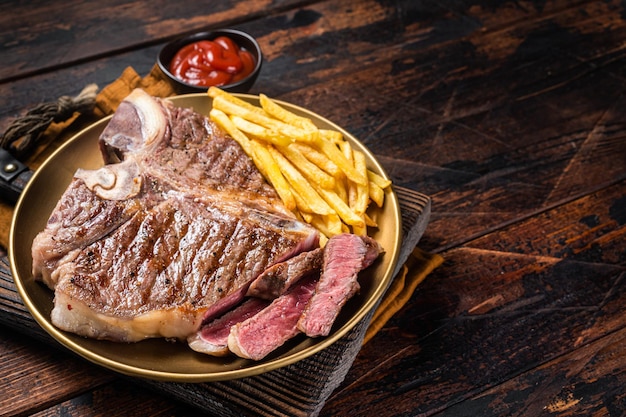 Asado italiano florentino o carne de res bistec en un plato con papas fritas Fondo de madera Vista superior Espacio de copia