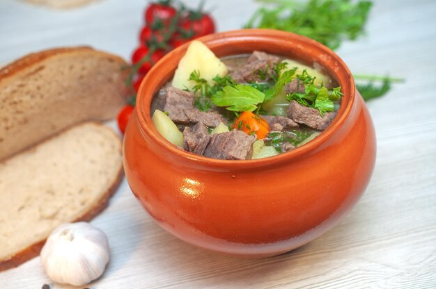 Asado en una olla con carne de res y papas en la mesa