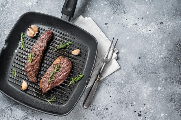 Asado en una sartén a la parrilla Aleta de flanco o bistec de carne de res Bavette con romero Fondo gris Vista superior Espacio de copia