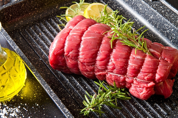 Asado de ternera con romero en una olla de placa sobre negro