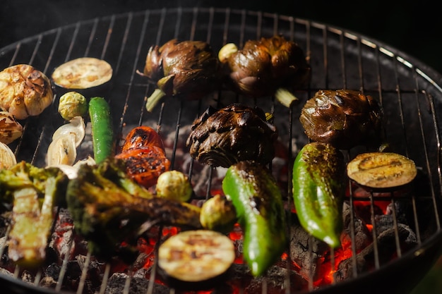 Asado verde Diversas verduras alcachofas pimientos berenjenas a la parrilla Nutrición vegana adecuada Fondo oscuro Carbones rojos