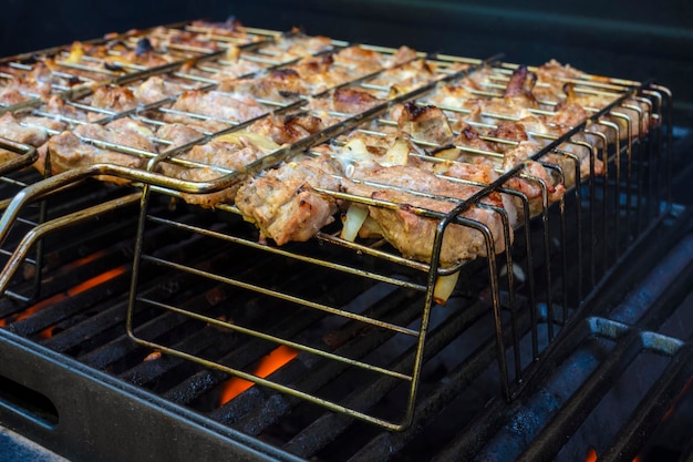 Asar carne o bistecs a la parrilla en llamas. Cocinar deliciosa comida afuera